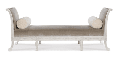A chaise lounge with a curved backrest and armrests that transition into the back. It features a long upholstered seat and is supported by four ornate legs. Two cylindrical bolster pillows are placed on the seat. The frame is finished in a distressed white paint with decorative carvings. — 3D model