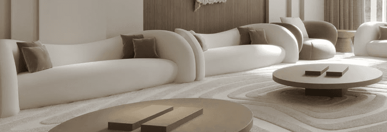A contemporary sofa with a distinct organic and curved silhouette, upholstered in a light, neutral fabric. It features seamlessly integrated, rounded armrests and a low, flowing backrest, creating a soft and inviting form. Two small, darker throw pillows are placed on the sofa. — 3D model