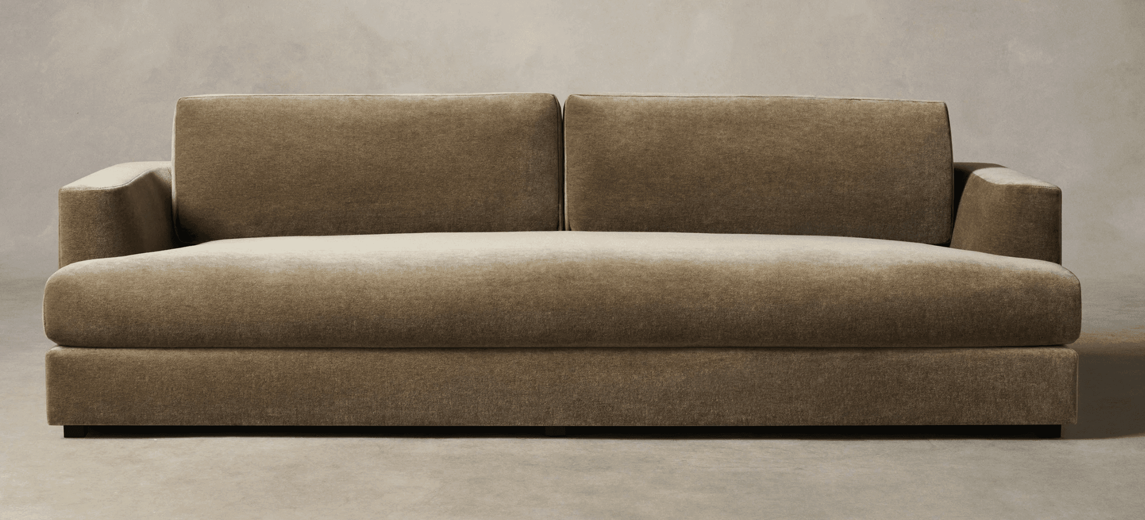 A contemporary two-seater sofa upholstered in a plush, olive green velvet or similar fabric, featuring a low-profile design, track arms, two distinct loose back cushions, and a single, long seat cushion. The sofa rests on discreet, recessed block feet, giving it a floating appearance. — 3D model