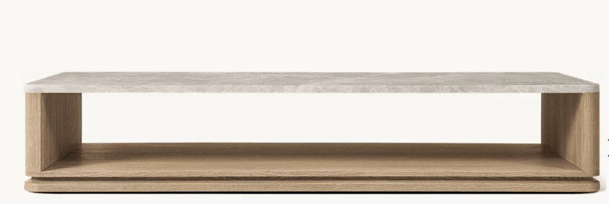 A modern, low-profile coffee table with a rectangular form. It features a composite or stone-like top surface with a light, speckled texture and a matte finish. The base is constructed from wood, showcasing a natural grain pattern and a light brown hue. The design incorporates an open shelf space beneath the tabletop, providing storage or display area. The edges are slightly rounded. — 3D model