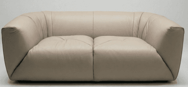 A modern two-seater loveseat upholstered in smooth, light beige leather, featuring a rounded, soft silhouette with integrated armrests and backrest. The backrest shows subtle vertical pleating, and the seat cushions have a distinctive stitched detail, while the base is concealed for a low-profile look. — 3D model