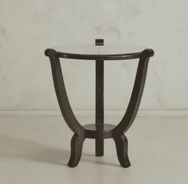 A circular end table with a light-colored, textured top and a dark wooden base. The base features a central circular shelf connected to three distinct legs, each with a curved top support. The legs have a dark, possibly stained or painted finish. — 3D model