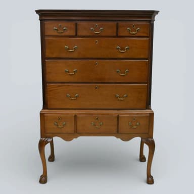 A traditional Queen Anne style highboy chest of drawers, constructed from medium-toned polished wood, featuring two stacked sections of multiple drawers with brass bail pulls, and supported by ornate cabriole legs ending in claw-and-ball feet. — 3D model