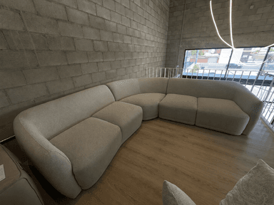 A contemporary light-colored curved modular sectional sofa upholstered in bouclé fabric, consisting of multiple rounded sections. — 3D model