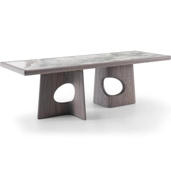 A contemporary dining table featuring a rectangular, variegated marble top supported by two substantial, sculptural wooden bases. Each wooden base is dark-stained, showcasing a visible wood grain, and includes a distinctive, irregular oval-shaped cutout. The design is modern and artistic. — 3D model