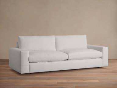 A modern, upholstered sofa viewed from the back. It features clean lines, square arms, and a relatively low profile. The upholstery appears to be a textured fabric in a light color. The sofa has two distinct back cushions and an extended base. — 3D model
