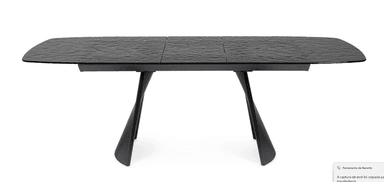 A contemporary dining table with a textured, dark surface and a black, ribbed pedestal base. The tabletop appears to be segmented and has a slightly irregular, wave-like texture. The base consists of two flared, curved legs with a ribbed pattern running vertically. — 3D model