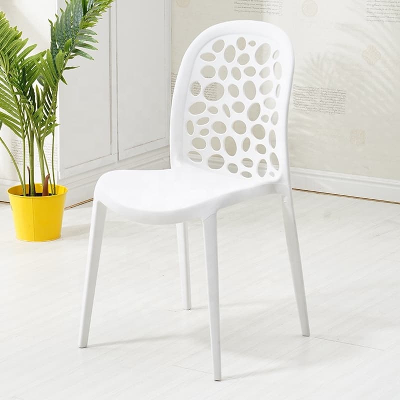 A modern white armless chair made of molded plastic, featuring a distinctive backrest with irregular perforated cutouts and four tapered legs. — 3D model