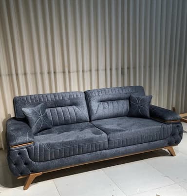 A contemporary three-seater sofa upholstered in dark gray fabric, featuring deep button tufting on the exterior side panels and channel stitching on the back cushions. It has light wood accents on the armrests and angled wooden legs. — 3D model
