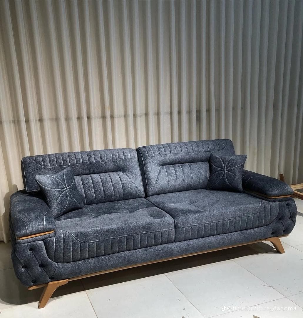 A contemporary three-seater sofa upholstered in dark gray fabric, featuring deep button tufting on the exterior side panels and channel stitching on the back cushions. It has light wood accents on the armrests and angled wooden legs. — 3D model
