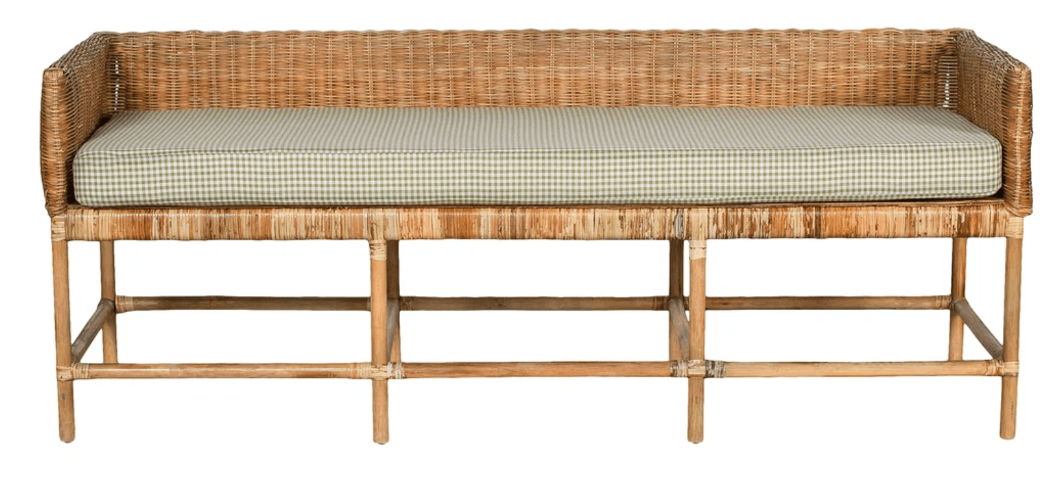 A long, rectangular bench featuring a woven rattan body with low, integrated armrests and a backrest. It is supported by a light-toned wooden or bamboo-style frame with horizontal and diagonal cross-supports. A light green and white checkered pattern cushion rests on the seating surface. — 3D model