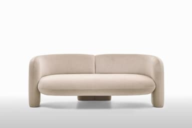 A contemporary loveseat upholstered in a light, neutral fabric, featuring a distinctive curved backrest and integrated rounded armrests. The piece has a monolithic appearance with no visible legs, suggesting a continuous, low-profile base. The design emphasizes soft lines and a plush, inviting form, suitable for modern interior settings. The fabric appears to have a subtle texture. — 3D model