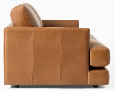 A contemporary two-seat loveseat upholstered in a warm, cognac-colored leather. It features a streamlined, low-profile design with plump, removable seat and back cushions. The armrests are subtly integrated, appearing as low, rounded track arms. The base is simple and rests on discreet, short feet, giving it a minimalist aesthetic. — 3D model
