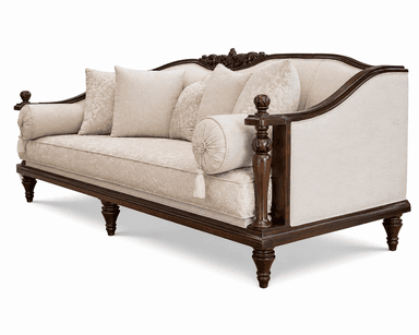 A traditional style sofa featuring a dark, elaborately carved exposed wooden frame and light-colored fabric upholstery. The sofa includes multiple decorative throw pillows and two cylindrical bolster pillows at each end. The back has a distinctive carved crest rail, and the legs are turned wood. — 3D model