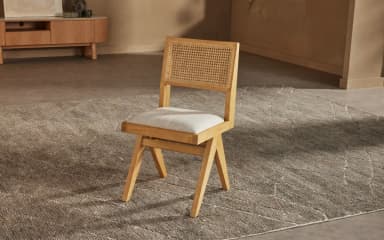 A modern dining chair with a minimalist design, featuring a wooden frame and a cushioned seat. The chair has a unique angular leg structure and a slightly reclined backrest. — 3D model