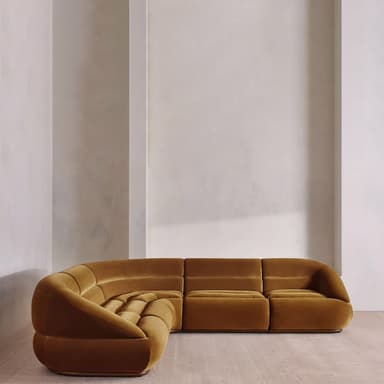 A modular sectional sofa with rounded edges and a plush velvet upholstery. The sofa is configured in a corner arrangement, featuring deep seats and back cushions with horizontal tufting. The design is low-profile and appears to be upholstered in a warm, mustard-yellow or ochre velvet fabric. — 3D model