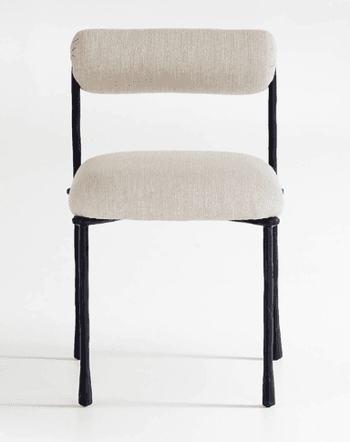 A modern armless chair featuring a dark-colored metal frame with an organic, somewhat irregular texture. It has a light beige or off-white upholstered seat cushion and a cylindrical, bolster-style backrest, also upholstered in the same fabric. The chair stands on four slender, tapered legs. — 3D model