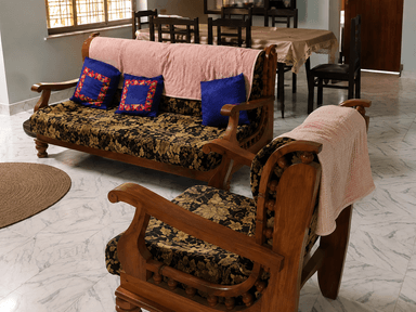 A traditional wooden sofa featuring a carved frame, dark floral pattern upholstery on the seat cushion, and accent pillows, partially covered by a light pink throw. — 3D model