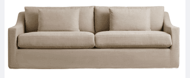 A contemporary three-seat sofa, upholstered in a light beige fabric, featuring a clean, tailored design. The sofa has a low-profile silhouette with slightly curved track arms and a continuous skirted base that conceals the legs. It is furnished with two large seat cushions and two loose back cushions, along with two rectangular accent pillows. The overall aesthetic is minimalist and inviting. — 3D model