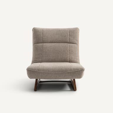 A modern armchair with a low profile and a sloped backrest. The armchair features upholstered seating and back cushions with subtle tufting. It is supported by a minimalist wooden base with angled legs. — 3D model