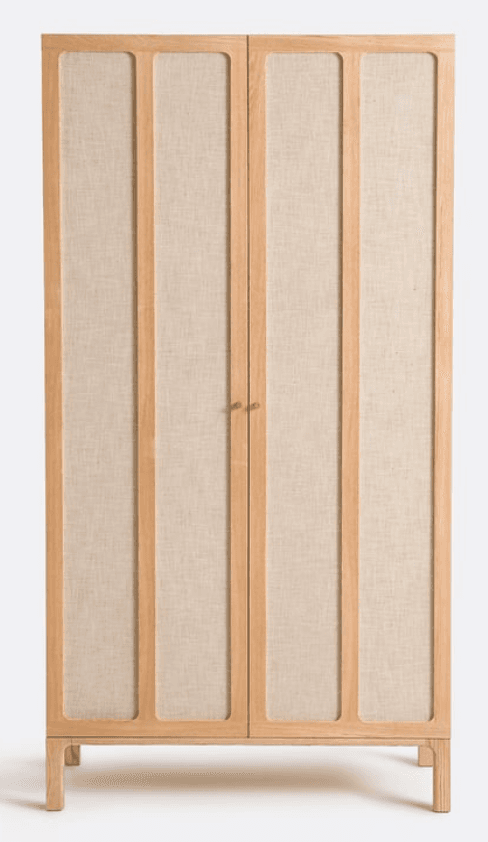 A tall, rectangular storage unit featuring two full-height doors. The doors are constructed with light-toned wooden frames and multiple vertical stiles, enclosing light-colored, textured woven fabric panels. The unit stands on a subtle, integrated wooden plinth base and is equipped with small, round wooden handles at the center seam. — 3D model