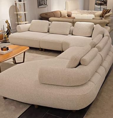 A large, light-colored, modular sectional sofa with multiple curved sections, upholstered in a textured fabric, featuring a low profile and small wooden feet. — 3D model