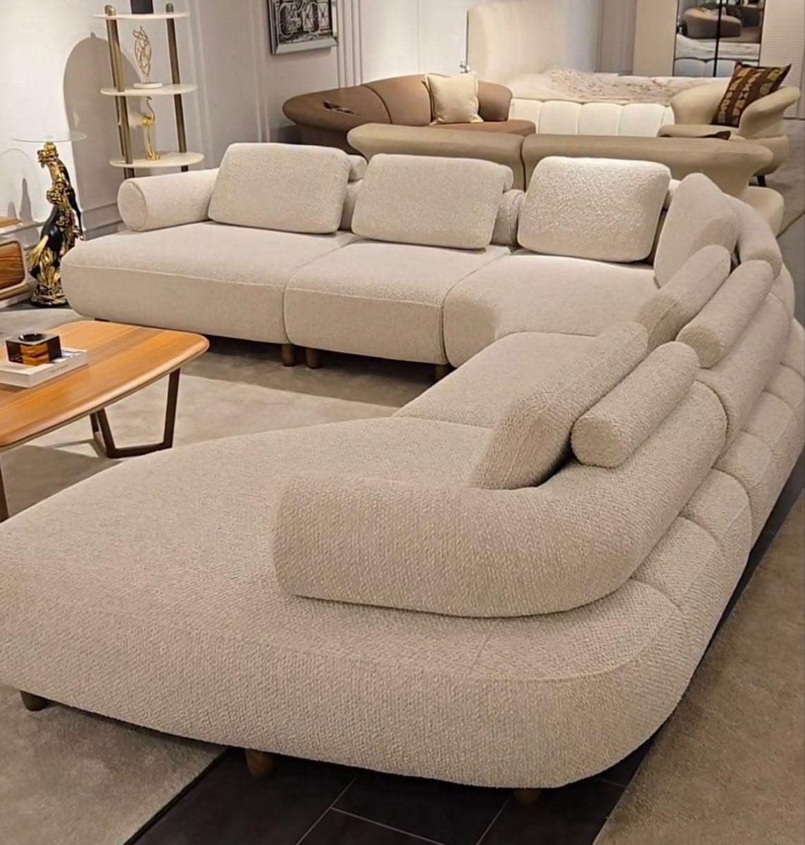 A large, light-colored, modular sectional sofa with multiple curved sections, upholstered in a textured fabric, featuring a low profile and small wooden feet. — 3D model