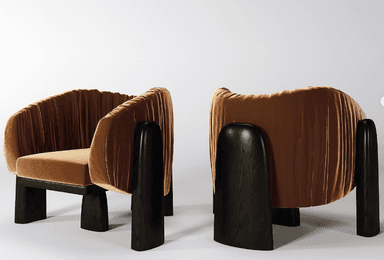 An upholstered lounge chair featuring a barrel-back design, covered in pleated burnt orange velvet, with integrated dark stained wood armrests and legs. — 3D model
