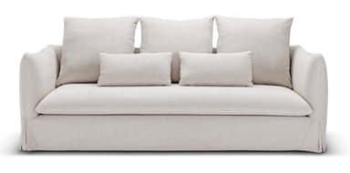 A contemporary sofa featuring a full slipcover in a light, neutral fabric. It has three large square back cushions and three smaller rectangular accent pillows, all loose. The arms are gently rolled or sloped, and the base features a skirted slipcover design. — 3D model