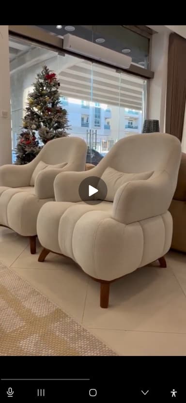 A modern, plush accent armchair with a rounded silhouette, upholstered in a textured, off-white boucle-like fabric featuring distinct channel tufting on the backrest and seat. It stands on four short, tapered wooden legs. — 3D model