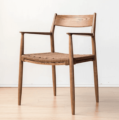 A Scandinavian-style armchair featuring a solid wooden frame with a curved backrest and integrated armrests. The seat is constructed from a natural woven material, likely paper cord, providing a textured surface. The chair has four tapered legs and a minimalist aesthetic. — 3D model