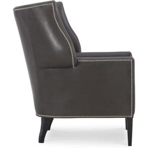 A dark brown accent chair upholstered in leather, featuring a high back with subtle wingback elements. The edges of the chair are adorned with decorative brass nailhead trim. The chair has four tapered legs made of dark wood. — 3D model