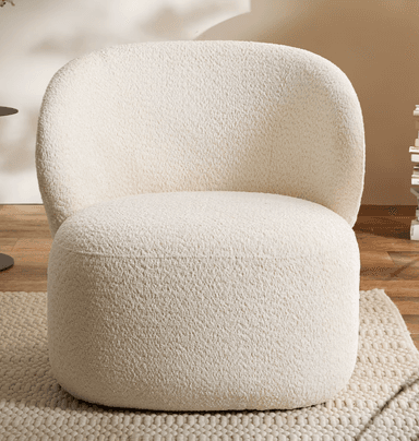 A contemporary lounge chair upholstered in a textured, cream-colored bouclé fabric. The chair features a distinctive, organic silhouette with a rounded back that seamlessly transitions into the armrests and seat, creating a unified and inviting form. Its low profile and plush cushioning suggest comfort and relaxation, making it a statement piece for modern interiors. — 3D model