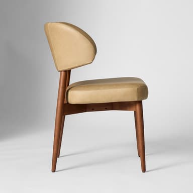 A tan upholstered accent chair with a curved backrest and a cushioned seat. The chair features a wooden frame with four tapered legs. The upholstery appears to be leather or a leather-like material, with visible stitching details on the backrest and seat cushion. The wooden legs and frame have a medium-toned finish. — 3D model