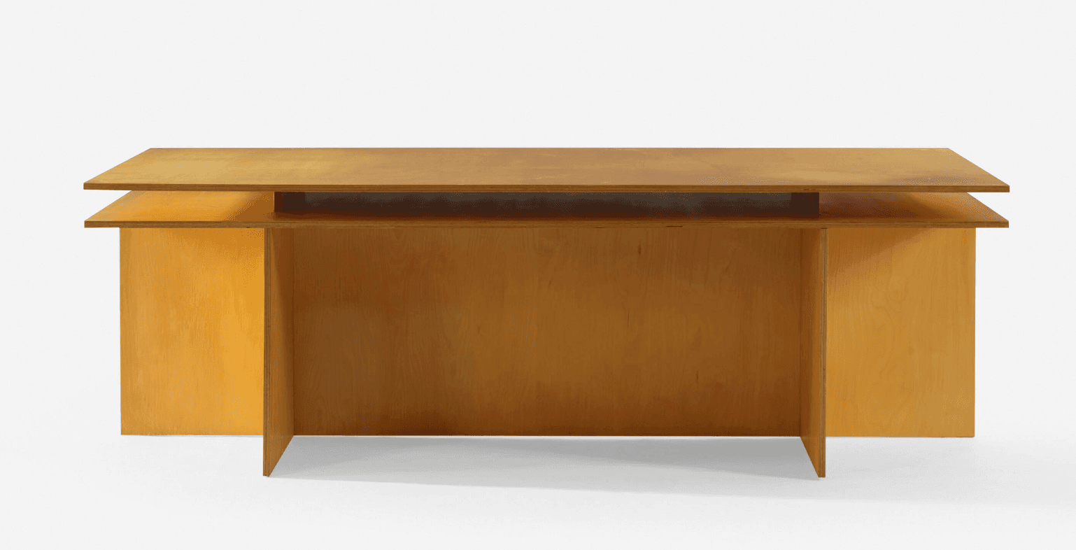 A minimalist desk constructed from light-colored plywood, featuring a distinctive floating top design. The desk is supported by two solid panel legs on the sides and a central full-height panel that also functions as a modesty panel. The layered edges of the plywood are visible, enhancing its modern aesthetic. — 3D model
