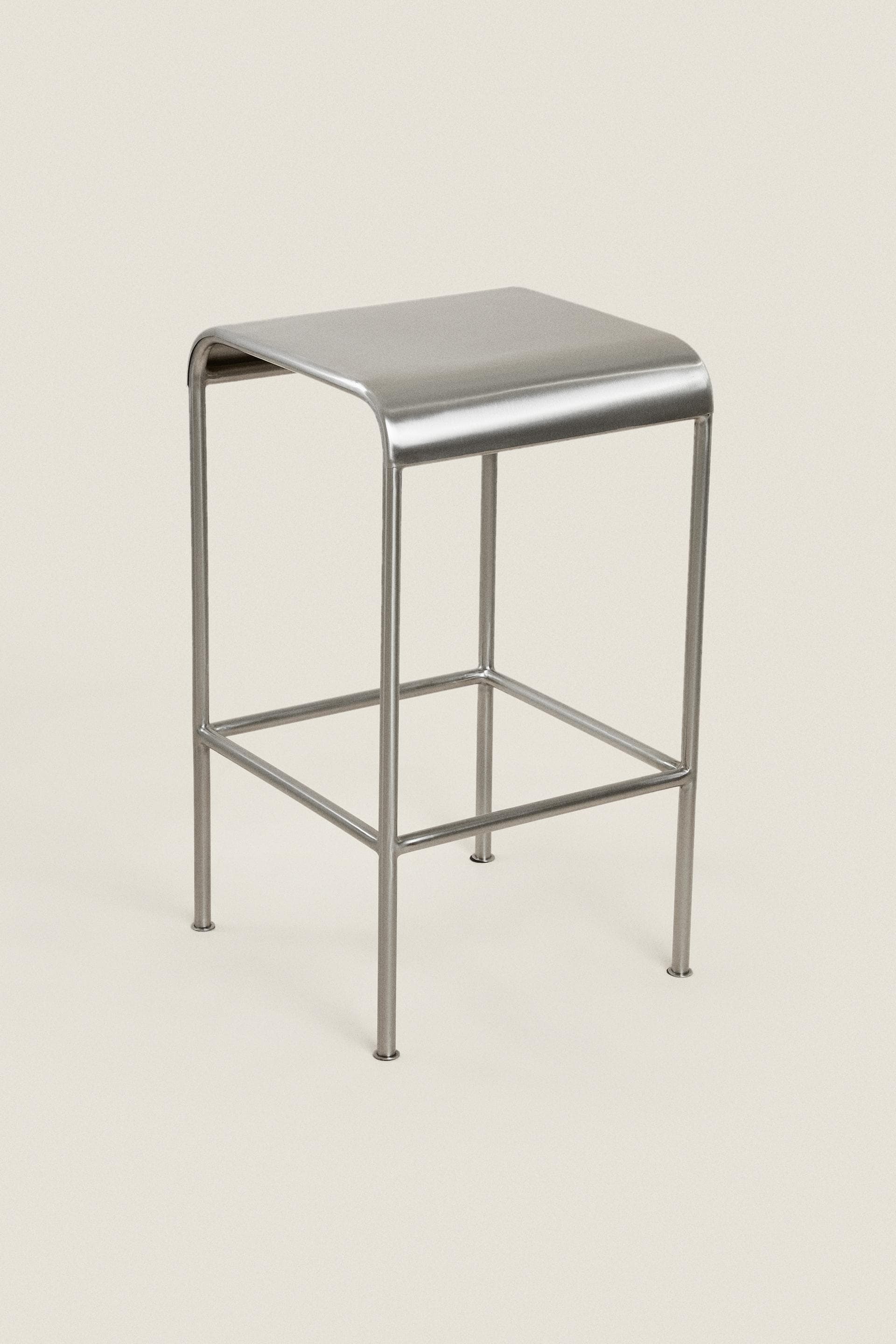 A minimalist, rectangular stool constructed entirely from brushed metal, featuring a seat with gently rounded corners and a tubular frame with integrated horizontal support bars. — 3D model