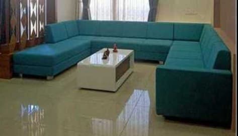 A large U-shaped sectional sofa upholstered in a vibrant teal textured fabric, featuring low, integrated armrests and backrests, individual seat and back cushions, and short metallic block feet. The sofa includes a prominent chaise lounge on one end. — 3D model