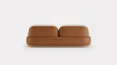 A contemporary two-seater loveseat featuring a dual-material design. The upper seating area, including the back cushions, seat cushions, and armrests, is upholstered in a light cream-colored, textured bouclé fabric, offering a soft and inviting appearance. The back and seat cushions are distinct, plump, and rounded. The lower perimeter of the sofa is encased in a smooth, curved tan-brown leather or faux leather panel, which provides a contrasting texture and color. This leather section is subtly elevated by a thin, light-toned wooden plinth base that forms the lowest part of the furniture piece, completing its minimalist and elegant aesthetic. — 3D model