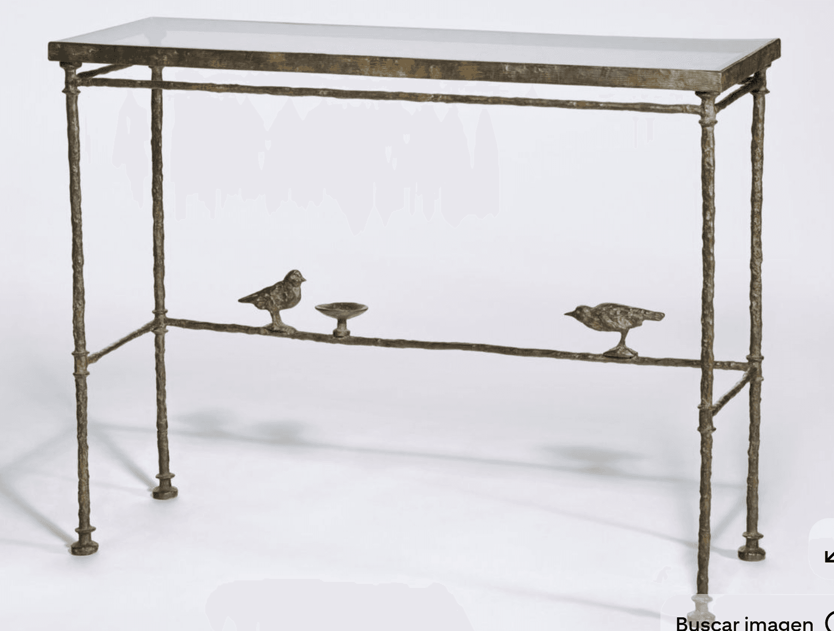 A slender console table with a glass top and a decorative metal base. The base is designed to resemble a branch, featuring two small bird figures and a small dish attached to a lower horizontal support. The legs are thin and textured. — 3D model