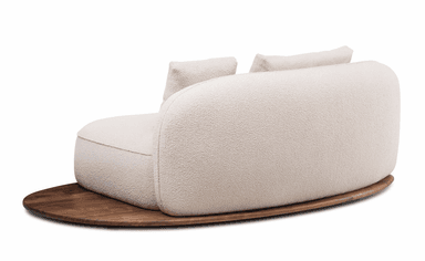A modern, curved sofa with a plush, textured upholstery and a distinct wooden base. The sofa features two loose back cushions and a rounded silhouette, resting on an oval-shaped, dark wood platform. — 3D model