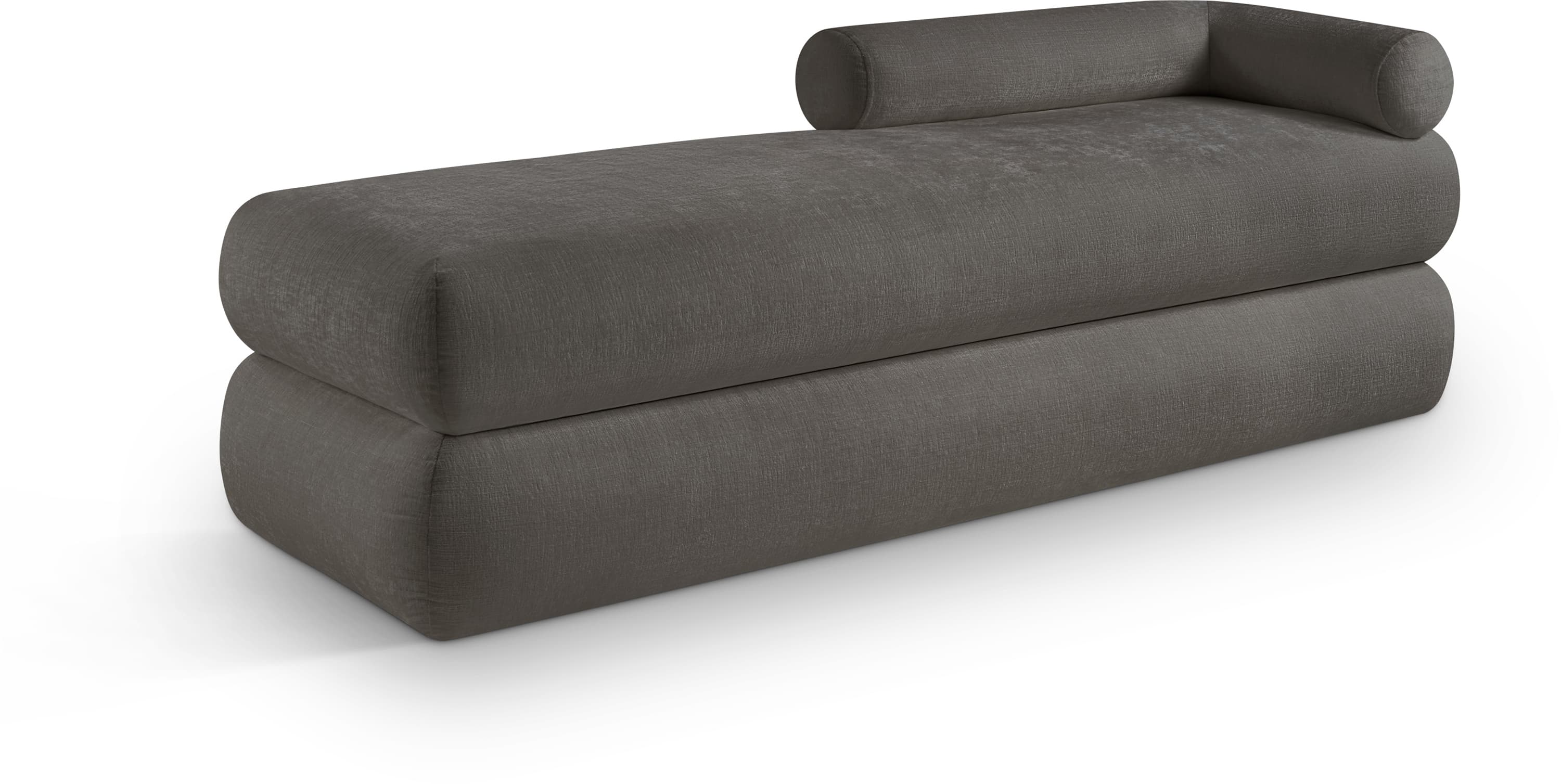 A contemporary chaise lounge featuring a rectangular, block-like base and an integrated top cushion, both upholstered in a dark grey textured fabric. A distinguishing cylindrical bolster is incorporated into one end, forming a backrest or armrest. The design is minimalist and robust, appearing as two stacked, rounded rectangular volumes. — 3D model