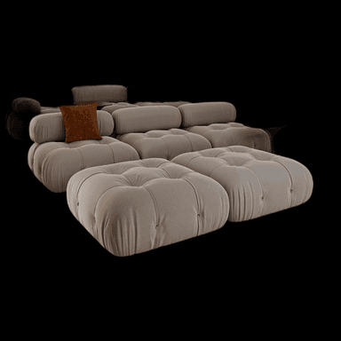 A modular tufted sofa with a low profile, featuring rounded, voluminous cushions and cylindrical armrests. The sofa is upholstered in a textured, light-colored fabric and includes several loose cushions and an ottoman. A single brown accent pillow is visible on one of the seat cushions. — 3D model