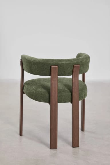 A modern accent chair featuring a curved upholstered backrest and seat in a textured green fabric. The chair has a visible wooden frame with four legs and armrests constructed from dark stained wood. The design is minimalist with clean lines. — 3D model