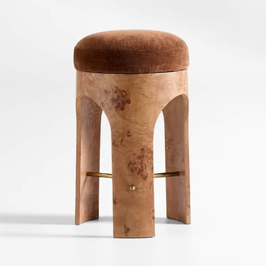 A stool with a rounded, upholstered seat and a pedestal base. The base is constructed from a wood veneer with a distinctive burl pattern, featuring an arched opening and supporting a subtle cross-brace. A small brass-colored knob is visible on each side of the base. — 3D model