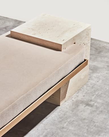 A modern bench featuring two substantial, rectangular stone block legs supporting a cushioned seat. The legs appear to be made of travertine or a similar porous, light-colored stone, with visible natural pitting. A thin, rectangular metal frame, likely brass or a similar golden-toned metal, spans between the legs and supports the seat cushion. The seat cushion is upholstered in a plain, light-colored fabric. — 3D model