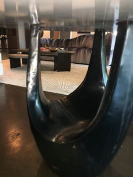A contemporary dining table featuring a round white tabletop supported by a distinctive dark, sculptural pedestal base with multiple organic lobes. — 3D model