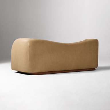 A contemporary two-seater loveseat upholstered in tan leather with a curved back and integrated armrests, resting on a dark wooden plinth base. — 3D model