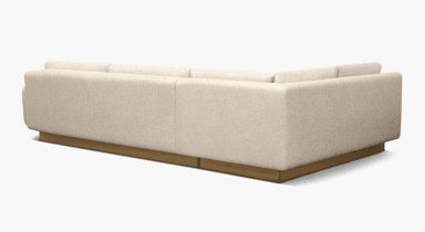 A modern sectional sofa with a low-profile wooden base. The sofa features upholstered cushions for the back and seat, and rounded armrests. The upholstery appears to be a textured light-colored fabric. — 3D model