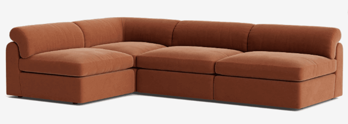A modular sectional sofa featuring a curved armrest on one end and a modular seating arrangement. The sofa has a low profile with plush cushions and a fabric upholstery. The color is a warm terracotta or burnt orange hue. — 3D model