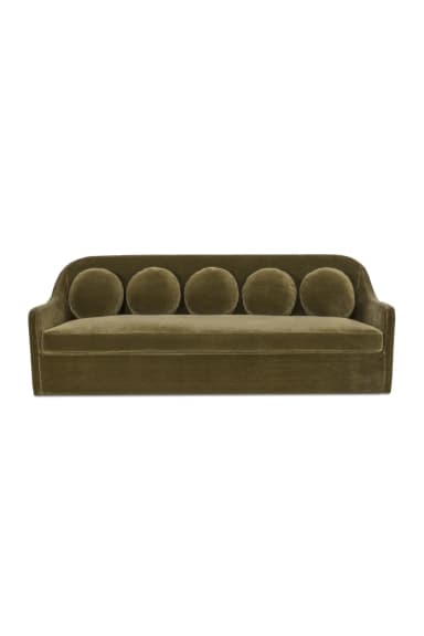 A contemporary velvet sofa featuring a low profile, integrated armrests that curve slightly upwards, and a single seat cushion. The backrest is adorned with five evenly spaced, circular bolster cushions. The overall design is sleek and modern, with clean lines and a plush upholstery. — 3D model